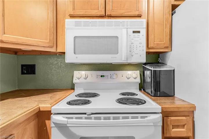 Wood cabinets, tile counter tops, dishwasher, range, microwave and refrigerator, reverse osmosis under sink for kitchen water,
