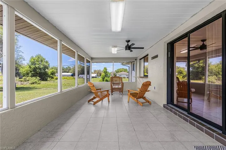 This screened-in patio features tiled flooring, a ceiling fan, and direct access to the interior via a large sliding glass door
