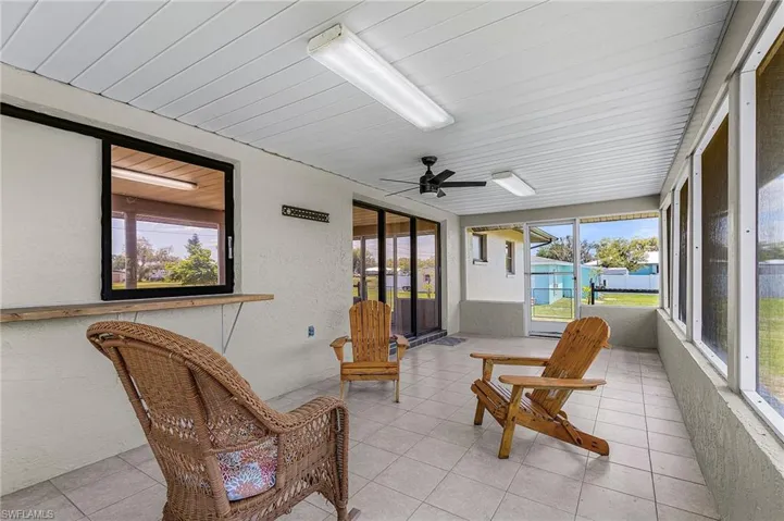 Expansive screened lanai approximately 22' x 11' featuring tiled flooring, pass through window to kitchen,  a ceiling fan,