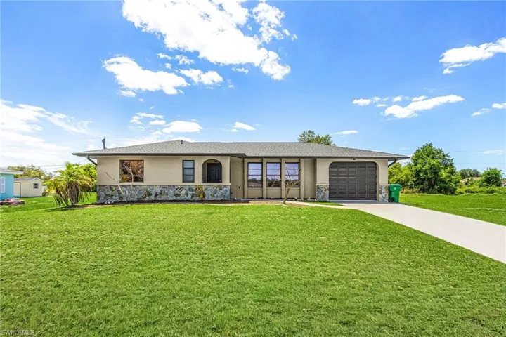 The property features a stucco exterior with a stone accent facade, a two-car garage, and a well-maintained lawn