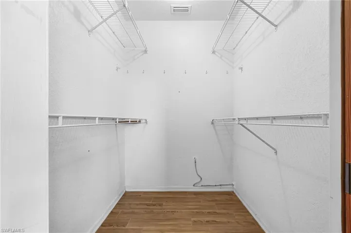 Spacious walk-in closet featuring wood-look flooring plank tile and built-in wire shelving