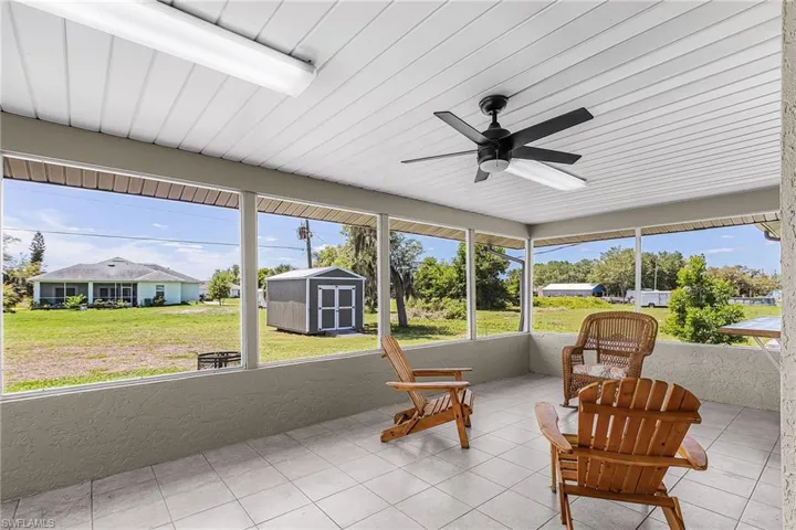 Expansive screened lanai approximately 22' x 11' featuring tiled flooring, pass through window to kitchen,  a ceiling fan,