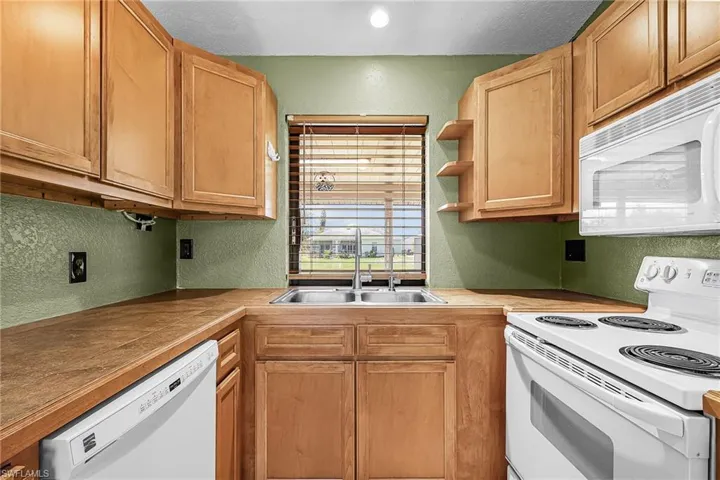 Wood cabinets, tile counter tops, dishwasher, range, microwave and refrigerator, reverse osmosis under sink for kitchen water, tile floors