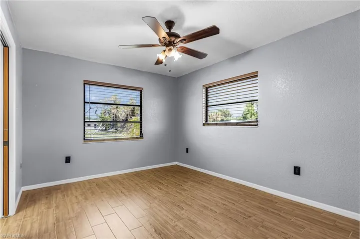 The room features two windows with blinds, a ceiling fan with light fixture, and wood-look flooring