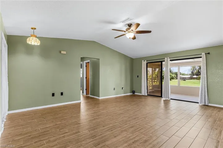 The living area features wood plank style tile flooring, sliding doors to spacious lanai, newer ceiling fan