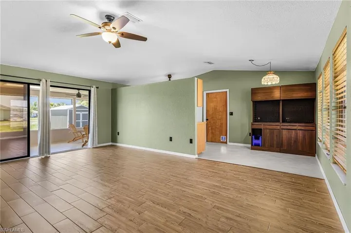 This living area features wood plank style tile flooring,  ceiling fan with integrated lighting