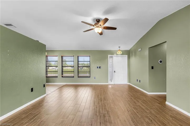 The living area features wood plank style tile flooring, sliding doors to lanai, newer ceiling fan