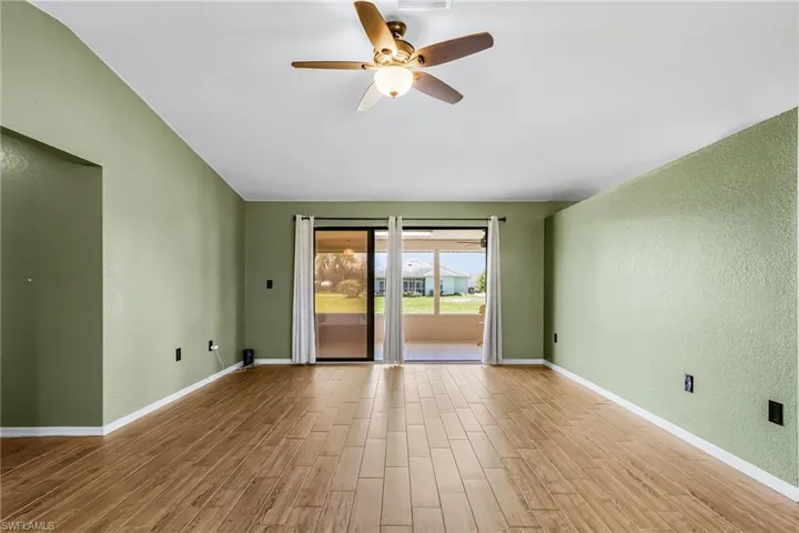 The living area features wood plank style tile flooring, sliding doors to spacious lanai, newer ceiling fan