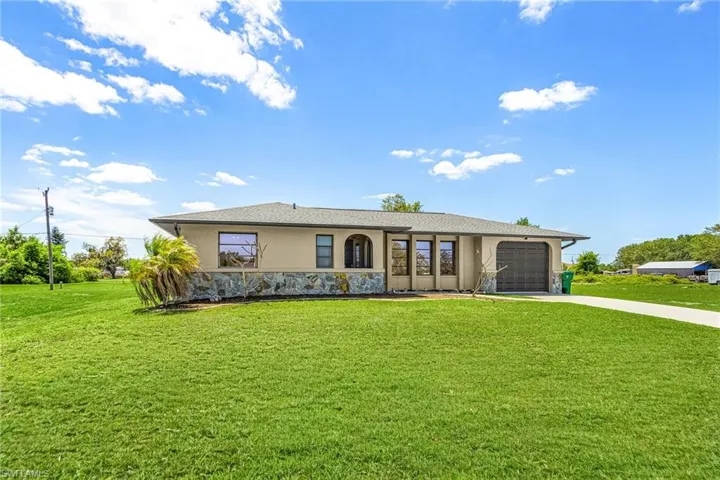 The property features a well-maintained lawn, a paved driveway, and an attached garage