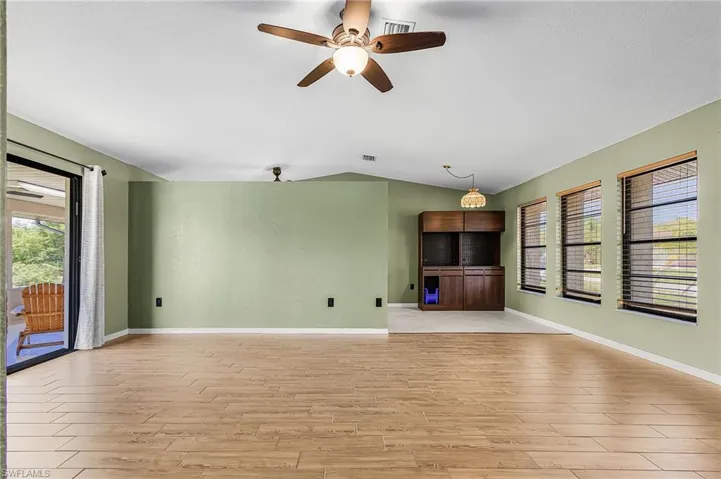 This living area features wood plank style tile flooring,  ceiling fan with integrated lighting