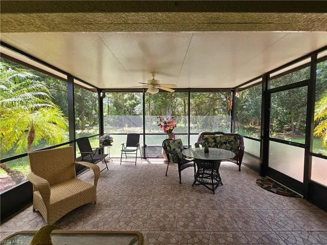 Screened lanai featuring a ceiling fan, patterned tile flooring, and a screened door