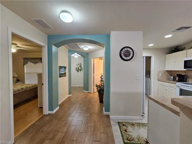 Hallway featuring wood-finish flooring, arched doorways, and recessed lighting