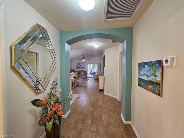 Hallway featuring wood-look tile flooring, an arched doorway, and recessed ceiling lighting