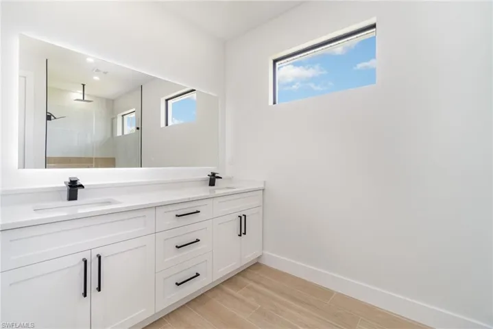 Bathroom featuring dual bowl vanity and a tile shower