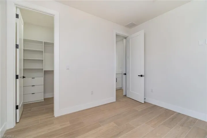 Unfurnished bedroom featuring a closet, light hardwood / wood-style flooring, and a walk in closet