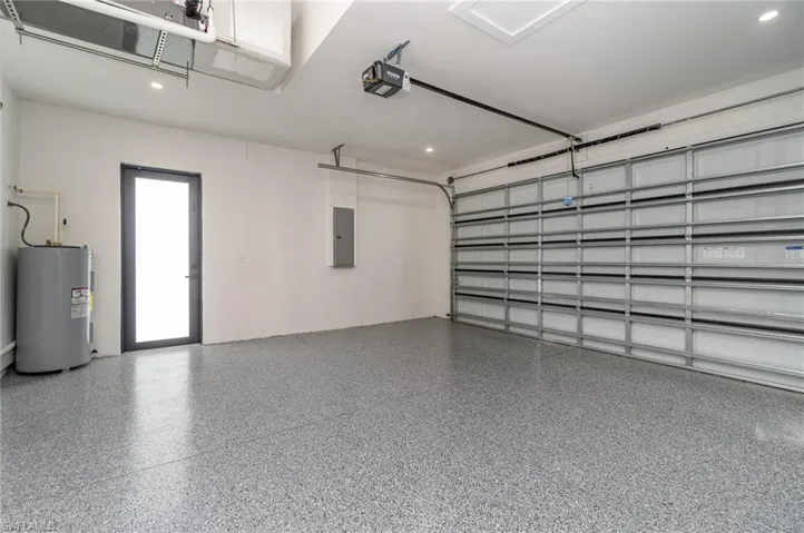 Garage with a garage door opener, electric water heater, and electric panel