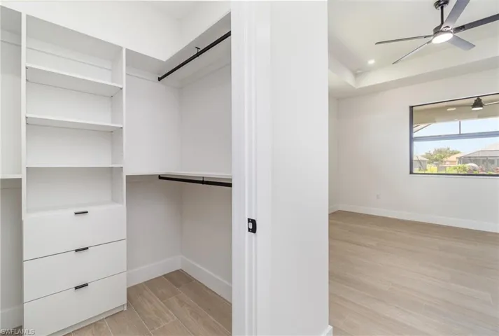 Spacious closet featuring ceiling fan and light hardwood / wood-style floors