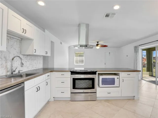 Kitchen with stainless steel appliances, a peninsula, white cabinetry, and recessed lighting