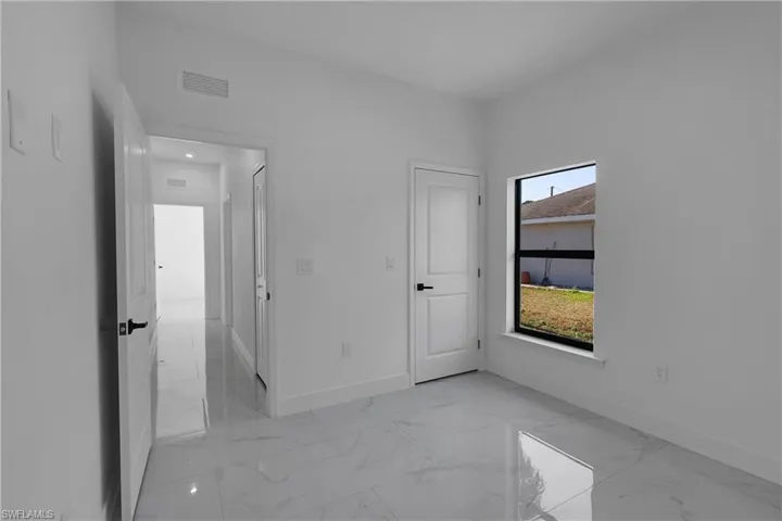 Unfurnished bedroom with light marble finish floors and baseboards