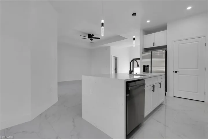 Kitchen featuring light marble finish flooring, white cabinets, pendant lighting, light stone countertops, and recessed lighting