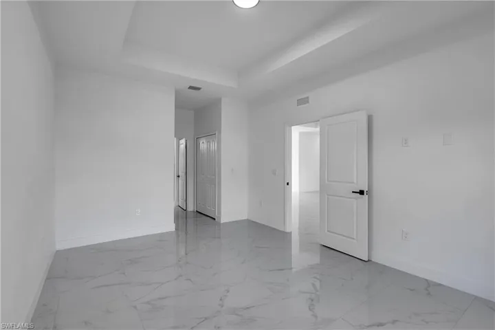 Empty room featuring light marble finish floors and a raised ceiling