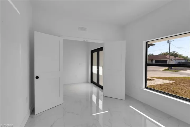 Unfurnished room featuring light marble finish floors and french doors