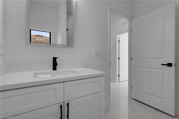 Bathroom featuring vanity and light marble finish floors
