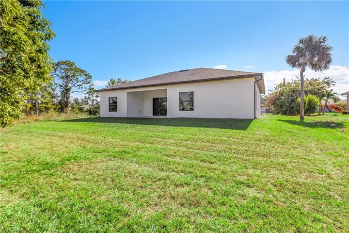 Rear view of property featuring a patio area, a yard, and stucco siding
