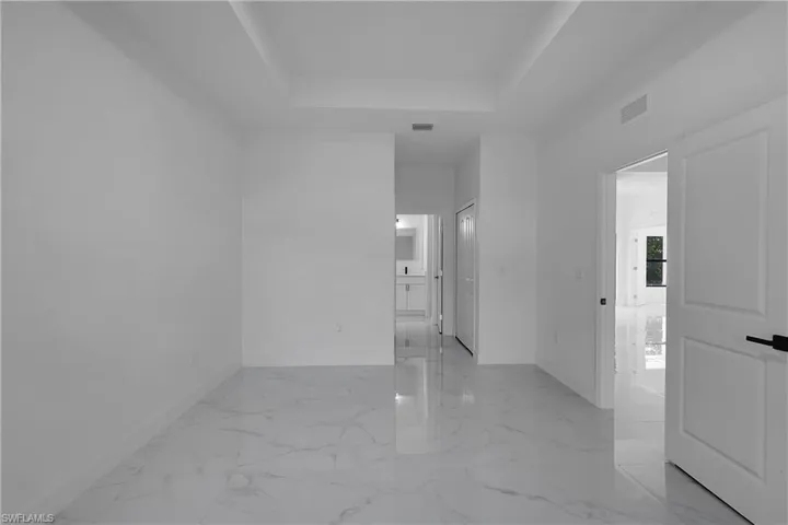 Spare room with a raised ceiling and light marble finish floors