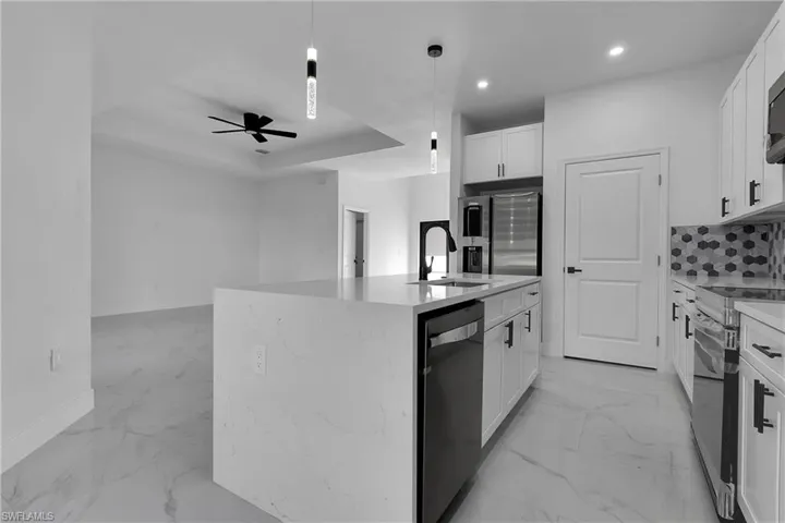 Kitchen featuring white cabinetry, light marble finish flooring, light stone countertops, and recessed lighting