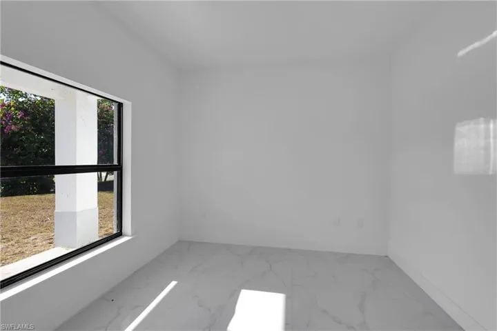 Unfurnished room featuring light marble finish floors and baseboards