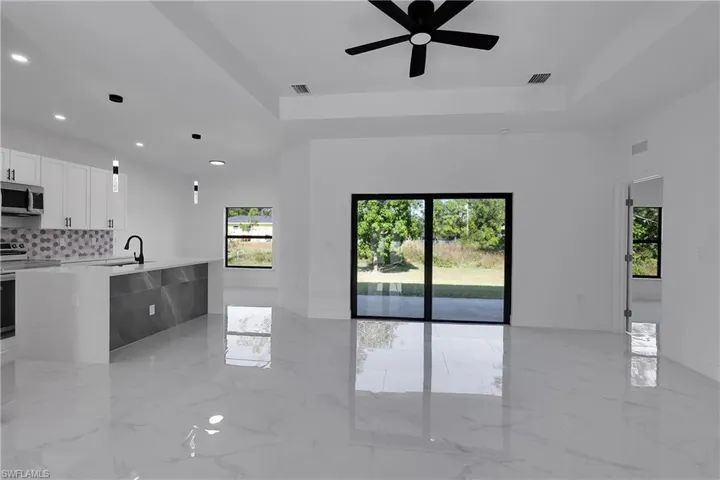 Unfurnished living room with light marble finish floors, ceiling fan, a raised ceiling, and recessed lighting