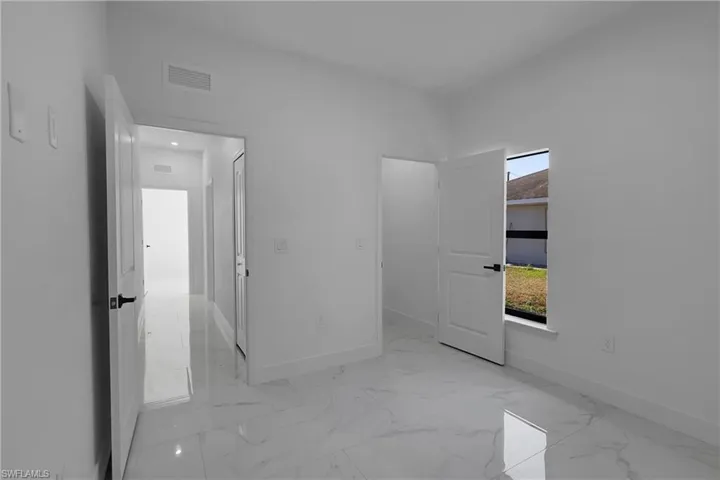 Unfurnished bedroom with baseboards and light marble finish floors