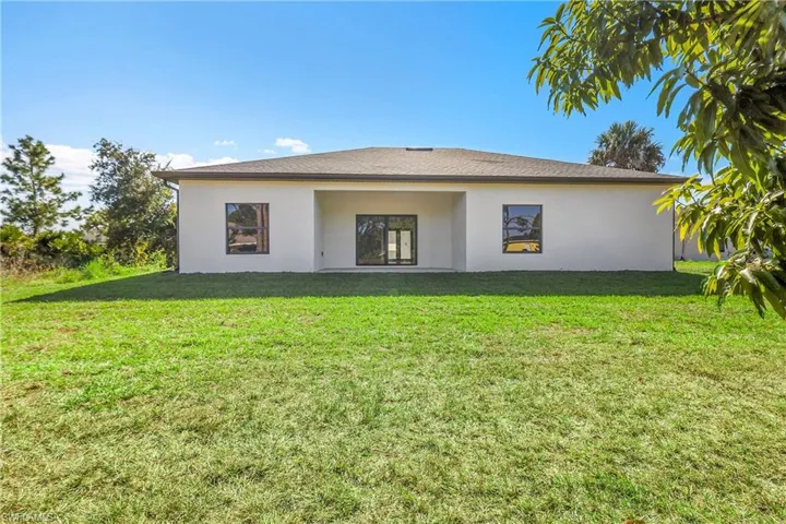 Rear view of house with a yard, stucco siding, and a patio