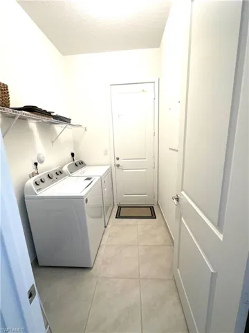Laundry room with a textured ceiling, washer and clothes dryer, and light tile patterned floors