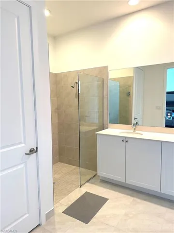 Bathroom featuring vanity, tile patterned flooring, and tiled shower