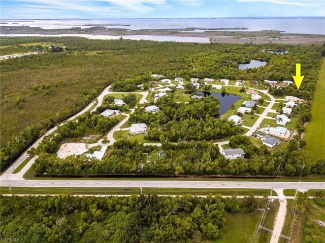Aerial perspective of suburban area featuring a large body of water and a heavily wooded area