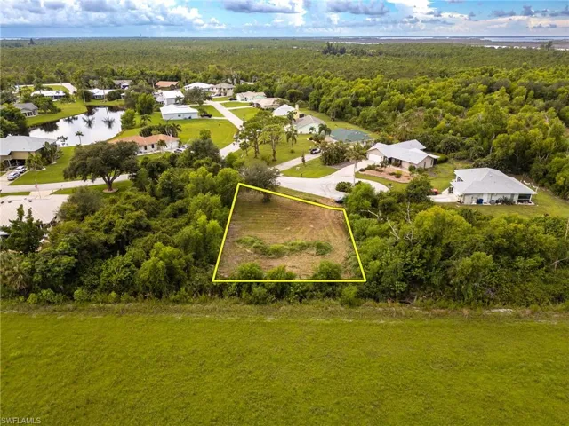 Aerial view of residential area featuring property boundaries highlighted and a nearby body of water