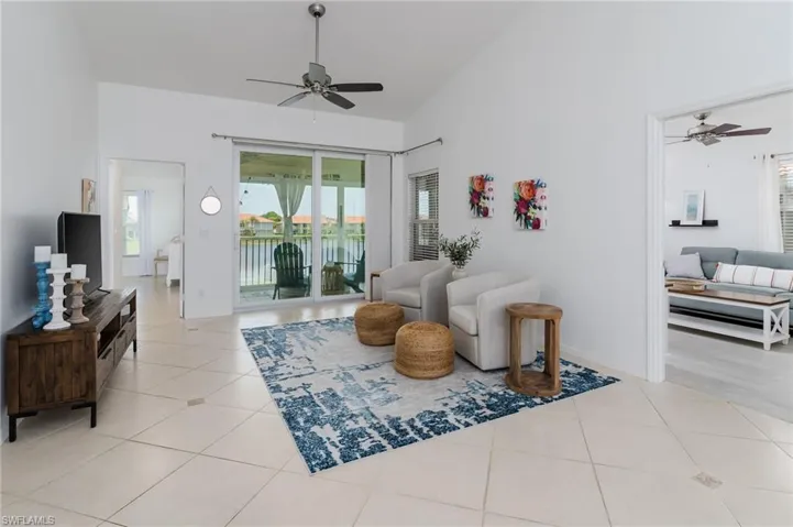 Tiled living area featuring ceiling fan and high vaulted ceiling