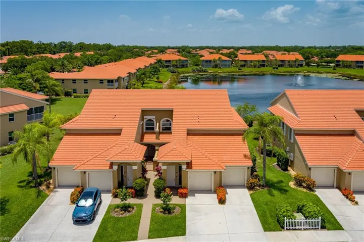 View of front facade featuring driveway, a tiled roof, a water view, and a garage