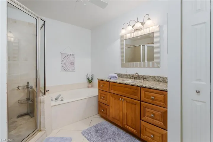 Full bathroom featuring a stall shower, vanity, a garden tub, a ceiling fan, and tile patterned flooring