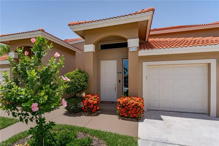 View of exterior entry featuring an attached garage, a tile roof, stucco siding, and concrete driveway