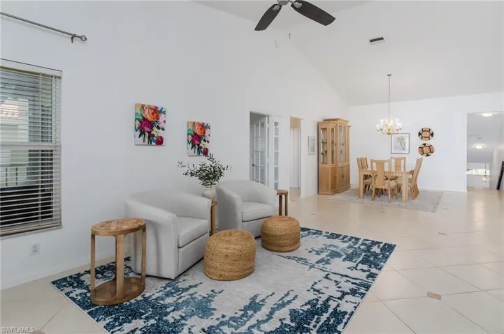 Sitting room with tile patterned floors, ceiling fan, high vaulted ceiling, and a chandelier