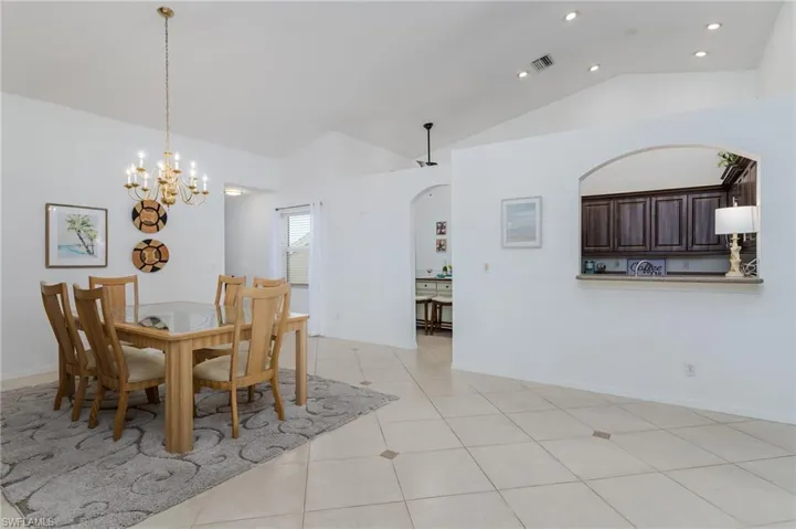 Dining area with lofted ceiling, recessed lighting, a chandelier, light tile patterned floors, and arched walkways