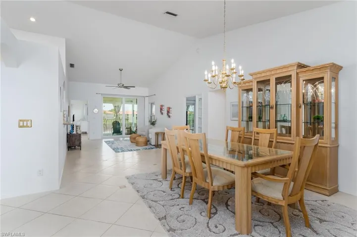 Dining space featuring a chandelier, high vaulted ceiling, light tile patterned flooring, a ceiling fan, and recessed lighting