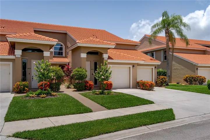 Mediterranean / spanish house with stucco siding, a tile roof, an attached garage, driveway, and a front lawn