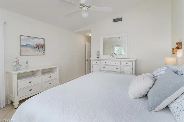 Tiled bedroom featuring vaulted ceiling and a ceiling fan