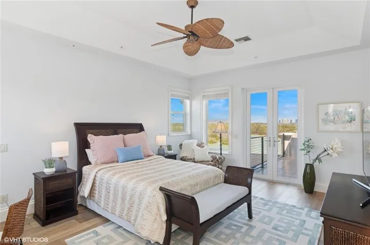Bedroom with access to exterior, visible vents, light wood finished floors, baseboards, and a raised ceiling