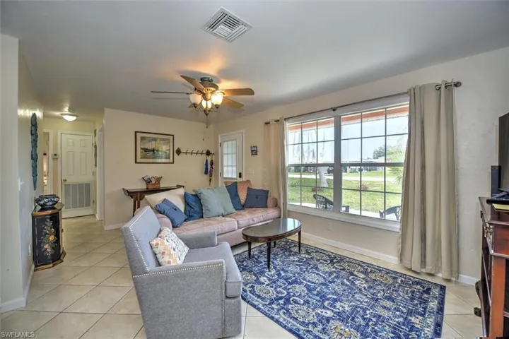 Living room with baseboards, ceiling fan, visible vents, and light tile patterned floors