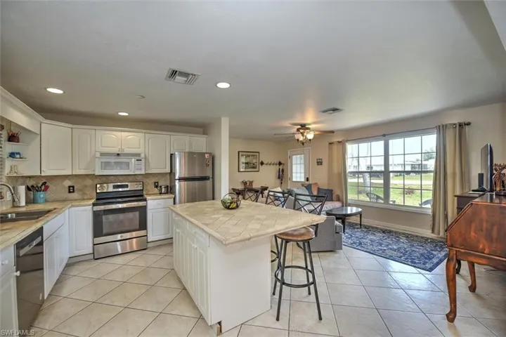 Kitchen featuring open shelves, a sink, a kitchen breakfast bar, stainless steel appliances, and visible vents